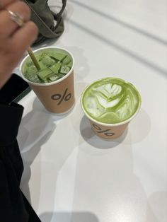 two cups filled with green liquid sitting next to each other on a white counter top