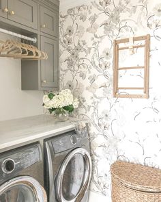 a washer and dryer in a laundry room with floral wallpaper on the walls