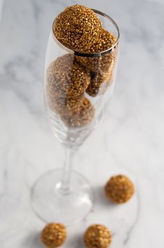 a glass filled with gold flakes sitting on top of a table next to three small balls