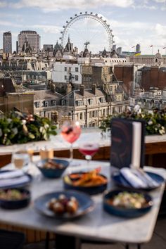 a table topped with plates of food next to a tall ferris wheel in the distance