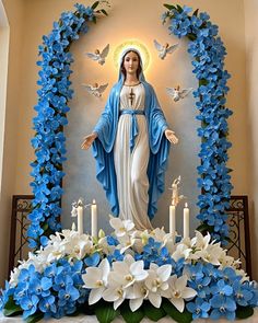 a statue of the virgin mary surrounded by blue and white flowers