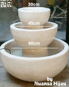 three white bowls sitting on top of each other in front of a glass case with measurements