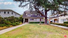 a house with trees in front of it and bushes around the yard on either side