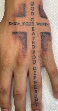 a person's hand with a cross tattooed on the wrist and words written across it