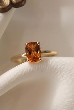 an orange sapphire ring sitting on top of a white cloth