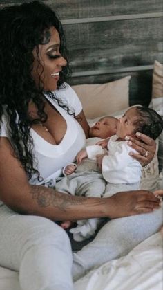 a woman sitting on a bed holding a baby