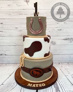 a three tiered cake with a cow print design on the top and rope around the bottom