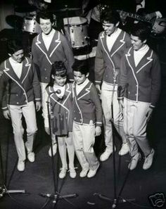 a group of men standing next to each other in front of microphones and drums