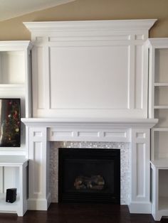 a living room with white bookcases and a fireplace