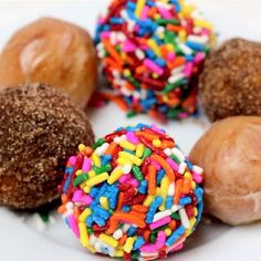 four donuts with sprinkles on a white plate