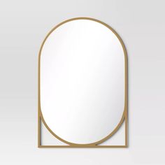 an oval mirror with a gold frame on a white wall, in the shape of a rectangle