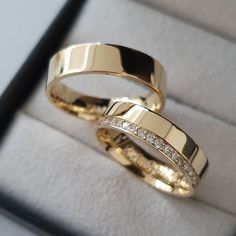 two gold wedding rings sitting in a box with diamonds on it's sides,