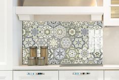 a kitchen with white cabinets and an ornate tile backsplash above the stove top