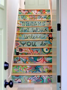 an open door leading to a colorful staircase with words painted on the steps and handrails