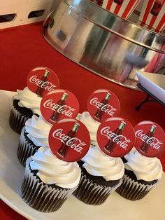 cupcakes with coca - cola stickers are on a plate