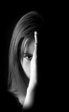 a black and white photo of a woman holding her hand to her face in the dark