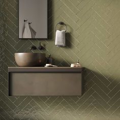 a bathroom with green wall tiles and a mirror above the sink in front of it