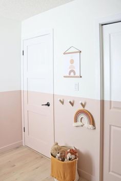 a child's room with pink and white walls, teddy bears in a basket