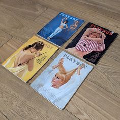 four magazines laying on top of a wooden floor next to each other and one has a woman's head