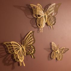 three metal butterflies mounted to the side of a wall next to each other on a pink wall