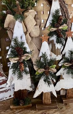 three wooden christmas trees with pine cones and bows on them, sitting in front of a burlwood background