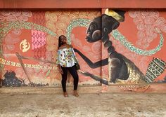 a woman standing in front of a wall with an elephant painted on it's side