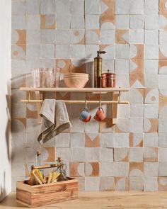 a shelf with pots, pans and other kitchen utensils on it in front of a tiled wall