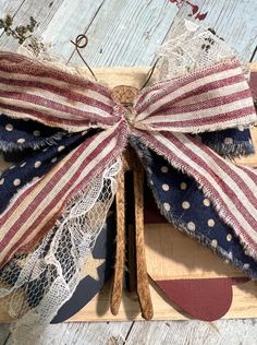 an american flag bow on a wooden board with lace and stars around it for patriotic decor