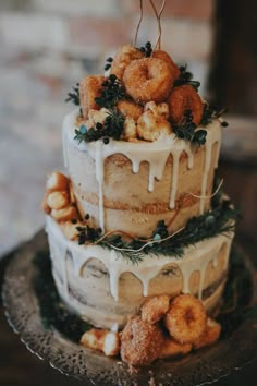 a three tiered cake with donuts on top and icing drizzled over it