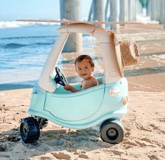 a baby in a toy car on the beach