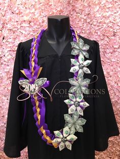 a black graduation gown with purple and gold flowers on the front, along with an elaborate necklace made out of dollar bills