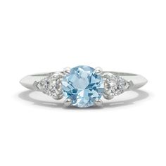 an oval blue topazte and diamond ring with three diamonds on the sides, in white gold