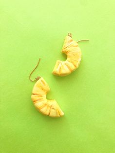 two pieces of fruit sitting on top of a green surface with gold ear wires attached to them