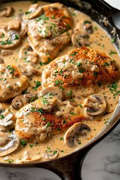 a skillet filled with chicken and mushrooms covered in gravy