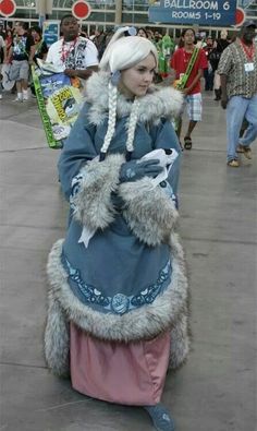 a woman dressed in costume is sitting on a bench with other people standing behind her