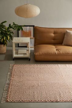 a brown couch sitting next to a white table on top of a carpeted floor