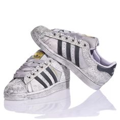 Adidas Superstar Bright Silver is the custom delicate and bold women's sneaker. Completely washed in silver with a white and silver glitter back and eyelets and gray satin laces. &nbsp;Adidas Superstar Bright Silver will also come with its original white laces. Silver Sneakers For Streetwear With Speckled Midsole, Silver Sneakers With Speckled Midsole For Streetwear, Metallic High-top Sneakers With Speckled Midsole, Metallic Sneakers With Speckled Midsole For Streetwear, Silver Lace-up Sneakers With Vulcanized Sole, Metallic Low-top Sneakers With Speckled Midsole, Silver Glitter Sneakers For Streetwear, Silver High-top Sneakers With Vulcanized Sole, Metallic Glitter Lace-up Sneakers