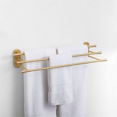 two white towels are hanging on a gold towel rack