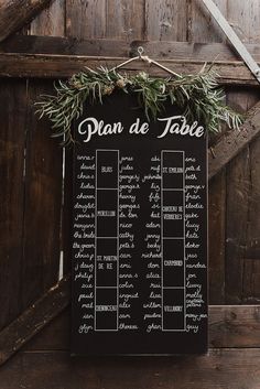 a table plan with greenery on it in front of a wooden wall and door