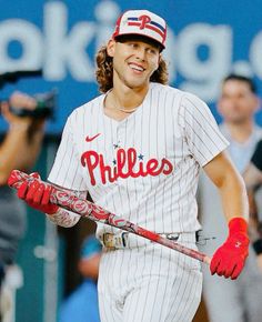 a baseball player holding a bat in his right hand and wearing red gloves on the other side