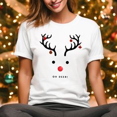 "Step into the festive spirit with our \"Oh Deer\" Reindeer Tee Shirt - the perfect blend of holiday cheer and trendy style for free-spirited souls!  No side seams mean there are no itchy interruptions under the arms. The shoulders have tape for improved durability. .: Made with medium fabric (5.3 oz/yd² (180 g/m consisting of 100% cotton for year-round comfort that is sustainable and highly durable.  .: The tear-away label means a scratch-free experience with no irritation or discomfort whatsoe Holiday White T-shirt With Graphic Print, White Graphic Tee For Holiday, Holiday White Graphic Tee Top, Holiday White Graphic Tee, White Holiday Graphic Tee, White Casual Christmas T-shirt, Casual White Christmas T-shirt, White Casual T-shirt For Christmas, White Graphic Print T-shirt For The Holiday