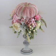 a vase filled with lots of flowers on top of a white table next to a wall