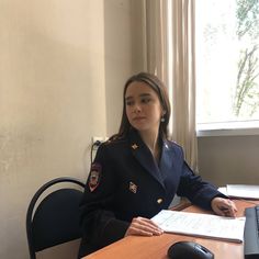 a woman in uniform sitting at a desk with a computer mouse and paper on it