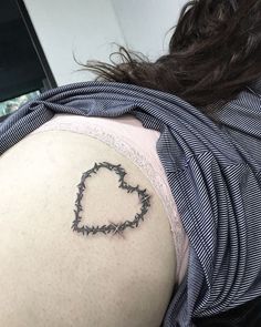 the back of a woman's shoulder with barbed wire in the shape of a heart