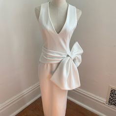 a mannequin wearing a white dress with a bow at the waist and back