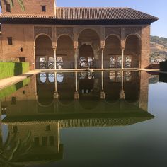 the reflection of an old building and its surrounding pool is seen in this photo taken on a sunny day