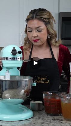 a woman standing in front of a mixer with ingredients on the counter next to her