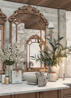 a bathroom with marble counter tops and gold mirrors on the wall, along with flowers in vases