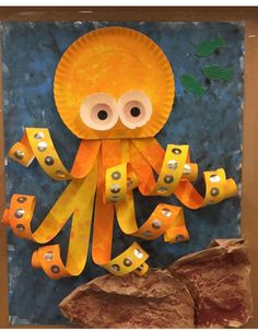 an octopus made out of construction paper on a blue background with gold tape and eyes