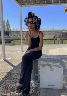 a woman sitting on top of a white box talking on a cell phone while wearing headphones